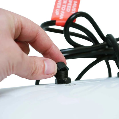 Hand tightening a black screw on a white object with a red label in the background